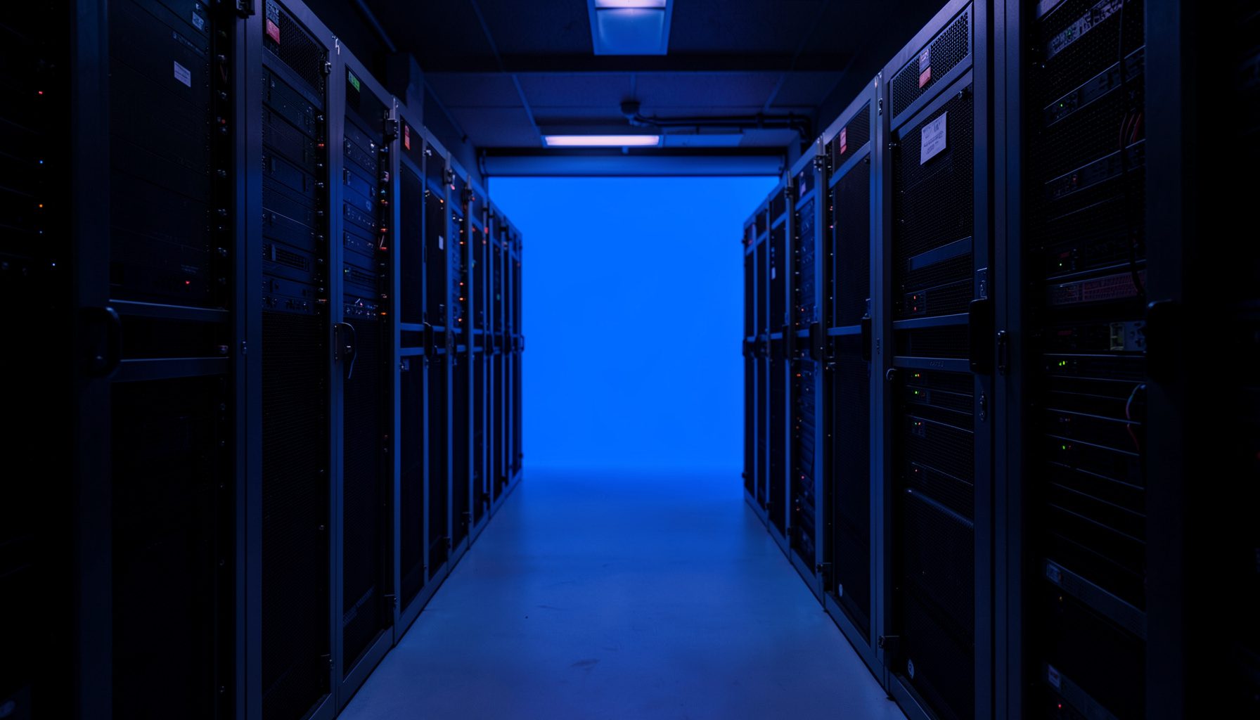Dark atmospheric server-room corridor with cool blue and violet ambient lighting, rows of rack-mounted equipment fading into shadow